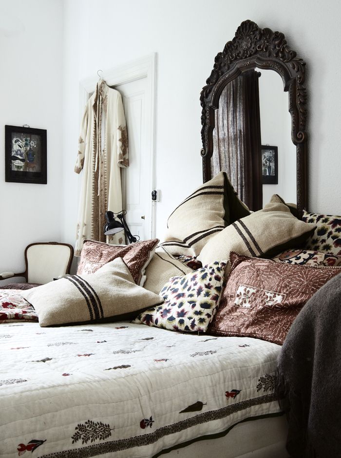 An old Indian mirror over a bed covered with a pile of pillows